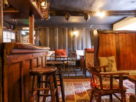 An interior room with wooden stools chairs a patterned rug and wooden paneling at The Old Church House Torbryan