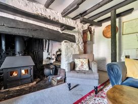 A living room with a fireplace and armchair at The Old Church House in Torbryan