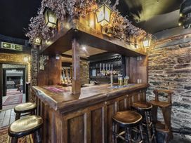 A bar area with wooden counter and stools at The Old Church House in Torbryan