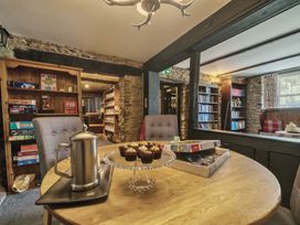 A snug room with a table of cupcakes and a bookshelf at The Old Church House in Torbryan