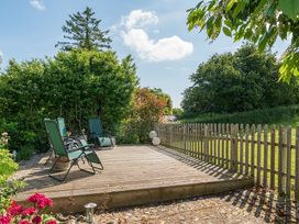 A decking area with chairs and flowers at The Old Church House in Torbryan