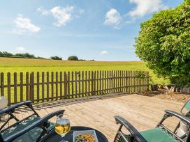 A deck area with chairs and food overlooking a field at The Old Church House in Torbryan