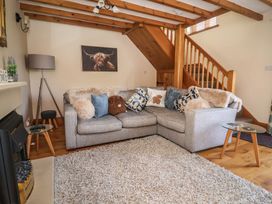 A living room with a sofa and a staircase at Ash Farm Cottage in Lixwm near Caerwys