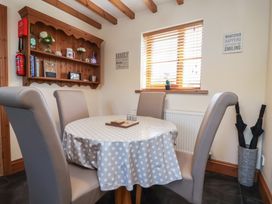 A dining room with a round table and chairs at Ash Farm Cottage in Lixwm near Caerwys