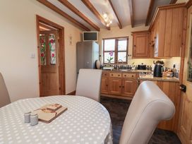 A kitchen with wooden cabinets and a dining table at Ash Farm Cottage Lixwm near Caerwys
