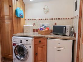 A utility room with appliances and storage at Ash Farm Cottage in Lixwm near Caerwys