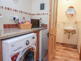 A laundry room with washing machine and microwave at Ash Farm Cottage Lixwm near Caerwys