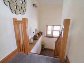 A hallway with a staircase and decorative items at Ash Farm Cottage in Lixwm near Caerwys