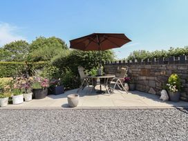 A garden area with table and chairs under an umbrella at Ash Farm Cottage Lixwm near Caerwys