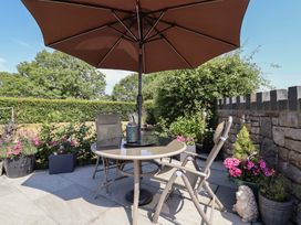 A garden with a table and chairs under an umbrella at Ash Farm Cottage Lixwm near Caerwys