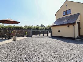 An outdoor area with a table and chairs under an umbrella at Ash Farm Cottage in Lixwm near Caerwys