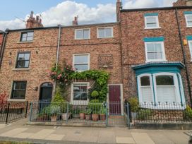 A brick residential house with potted plants and a red door at 5 College Square in Stokesley