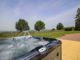 A hot tub with trees and a grassy area at Hunters Moon in Tenbury Wells