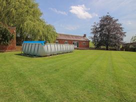 A garden with a swimming pool and trees at Hilltop House in Tenbury Wells
