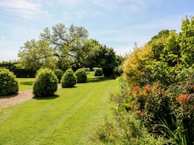 A garden with trees, bushes, and flowers at Hilltop House in Tenbury Wells