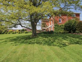 A garden with a large tree and a house at Hilltop House in Tenbury Wells