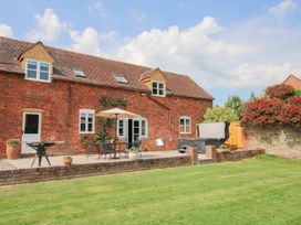 A brick house with a patio table and umbrella in a garden at The Chestnuts in Tenbury Wells
