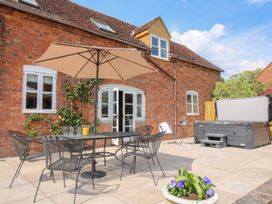 An outdoor patio with a metal table and chairs under an umbrella next to a hot tub at The Chestnuts in Tenbury Wells