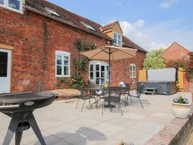 An outdoor patio with a barbecue grill table and umbrella chairs and a hot tub at The Chestnuts in Tenbury Wells