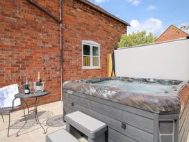 An outdoor area with a hot tub next to a brick wall and a small table with bottles and glasses