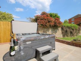 An outdoor patio with a hot tub a small metal table with champagne bottles and glasses at The Chestnuts in Tenbury Wells