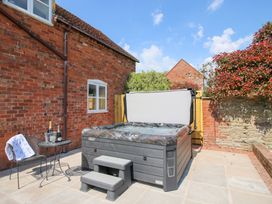 An outdoor patio with a hot tub steps table and chairs next to a brick house at The Chestnuts in Tenbury Wells