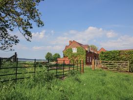 A brick house with ivy on the walls behind metal and wooden gates in a grassy field at The Chestnuts in Tenbury Wells