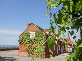 A brick house with ivy growing on the side and a patio area with a table and umbrella at The Chestnuts in Tenbury Wells