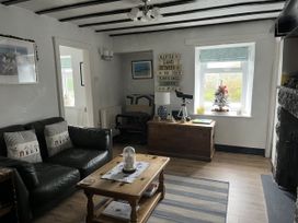 A living room with a sofa, coffee table, and armchair at Tyddyn Serri in Rhosneigr