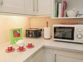 A kitchen countertop with a microwave, toaster, teapot, and teacups at Keepers Cottage, West Knoyle