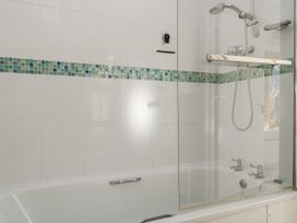 A bathtub with a shower and colorful tiles at Keepers Cottage in West Knoyle