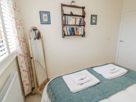 A bedroom with a bed, towels on the bed, and bookshelves at Keepers Cottage in West Knoyle