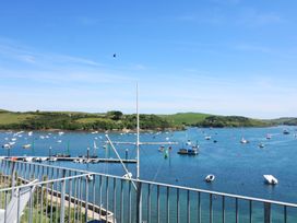 A view of a harbor with boats on water and green hills in the background taken from a balcony at 37 The Salcombe in Salcombe