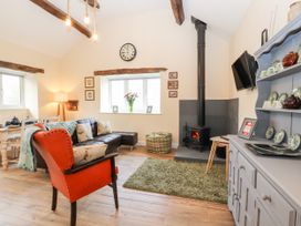 A living room with a wood stove and a sofa at Cut Moch, Plas Moelfre Hall Barns near Moelfre near Llanrhaeadr-Ym-Mochnant