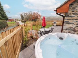 A garden with a hot tub and seating area at Cut Moch, Plas Moelfre Hall Barns Moelfre near Llanrhaeadr-Ym-Mochnant