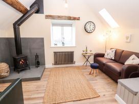 A living room with a stove and sofa at Stabl, Plas Moelfre Hall Barns, Moelfre near Llanrhaeadr-Ym-Mochnant