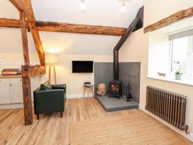 A living room with a sofa and wood stove at Stabl, Plas Moelfre Hall Barns Moelfre near Llanrhaeadr-Ym-Mochnant