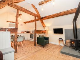 A living room with a kitchen area and wooden beams at Stabl, Plas Moelfre Hall Barns Moelfre near Llanrhaeadr-Ym-Mochnant