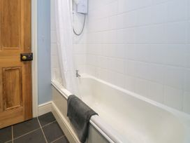 A bathroom with a bathtub and shower curtain at Sygun View in Beddgelert