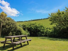 A picnic table on grass with bushes and a field at 4 Thornlea Mews in Hope Cove