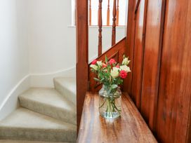 A staircase with a wooden railing and flowers in a vase at Preswylfa in Caernarfon