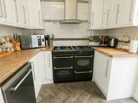 A kitchen with a stove, microwave, and sink at Preswylfa, Caernarfon