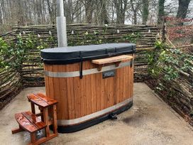 A wooden hot tub with a stool on a stone patio at Bracken Fern in Eppleby