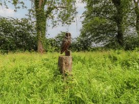 An owl statue on a tree stump in a grassy area at Bracken Fern in Eppleby