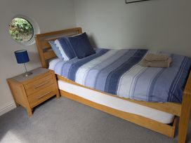 A bedroom with a bed, nightstand, lamp, and towels at Hawthorn Cottage St Teath