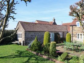 A garden with a cottage and seating area at Cartwheel Cottage in Yearsley