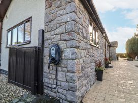 An outdoor area with an electric vehicle charger and stone wall at Arosfa in Axton near Trelawynd