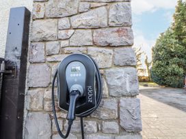 An electric vehicle charger mounted on a stone wall at Arosfa Axton near Trelawynd
