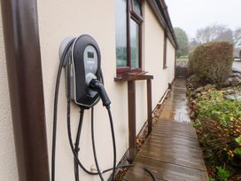 An electric vehicle charger mounted on a wall near a pathway at Arosfa in Axton near Trelawynd