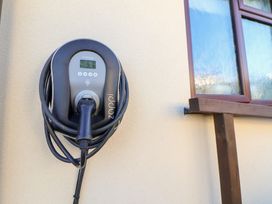 An electric vehicle charger mounted on a wall at Arosfa in Axton near Trelawynd